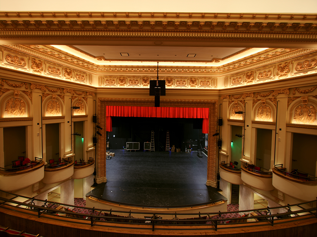 Ornate historic theater interior with balconies and red stage curtain at the Academy Center of the Arts