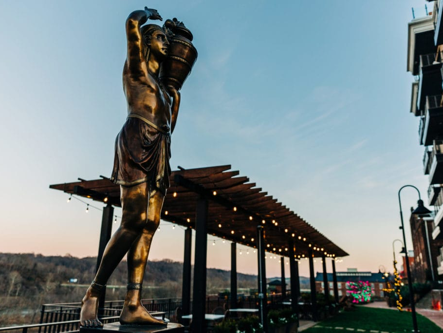 Bronze statue and string-lit pergola along the Bluffwalk at sunset in downtown Lynchburg